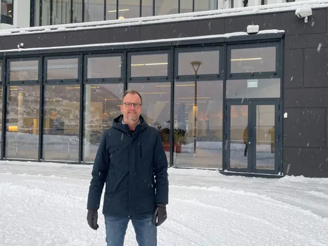 Mann i snøvær utenfor kontor