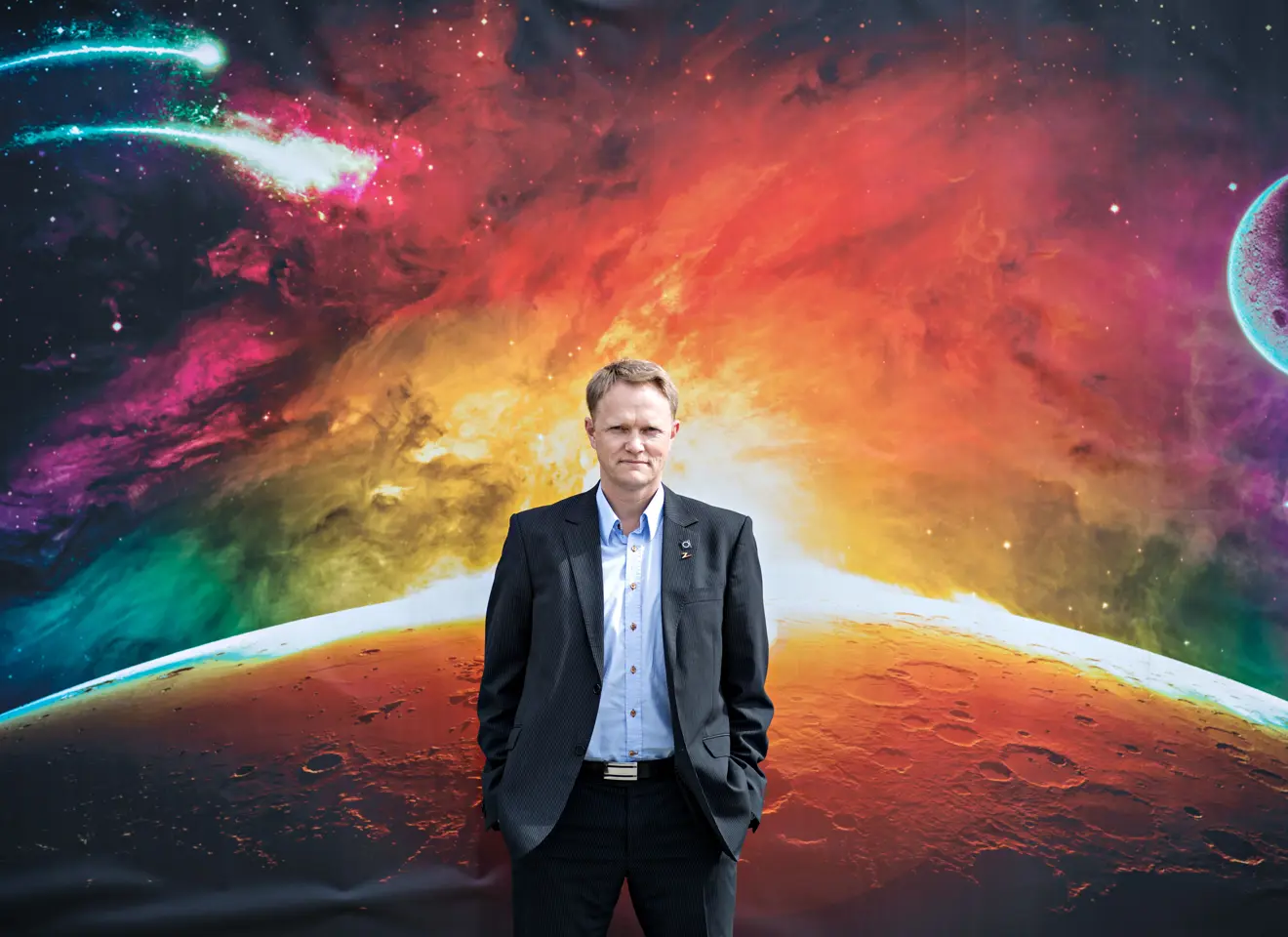Brage Johansen står foran en husvegg med planeter og universet malt på