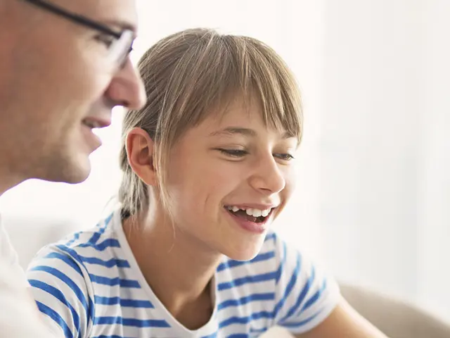 En mann som sitter ved siden av et smilende barn