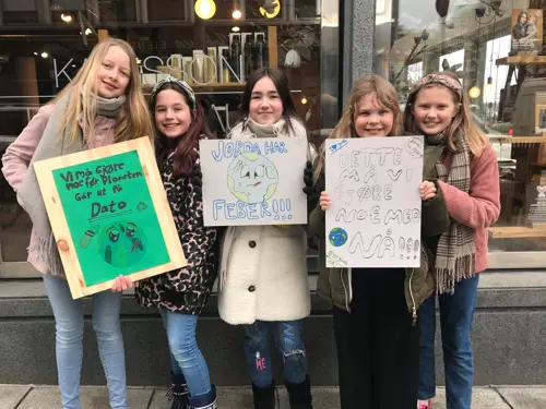 Fem unge jenter med plakater til støtte for klimakampen 