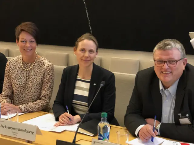 3 personer sitter og smiler til kamera