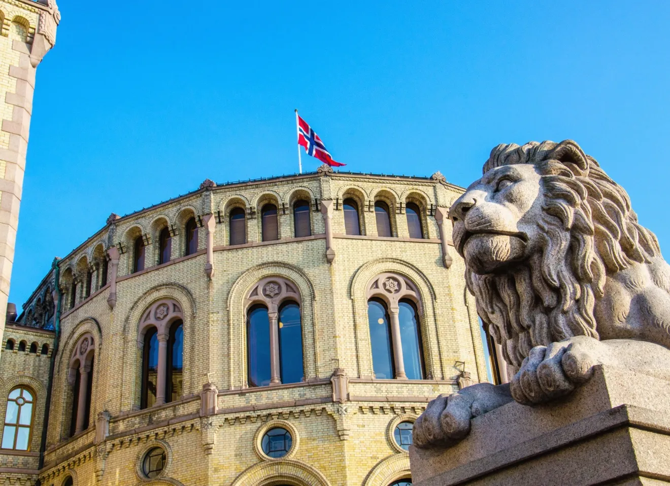 Nærbilde av en løvestatue med Stortinget i bakgrunn