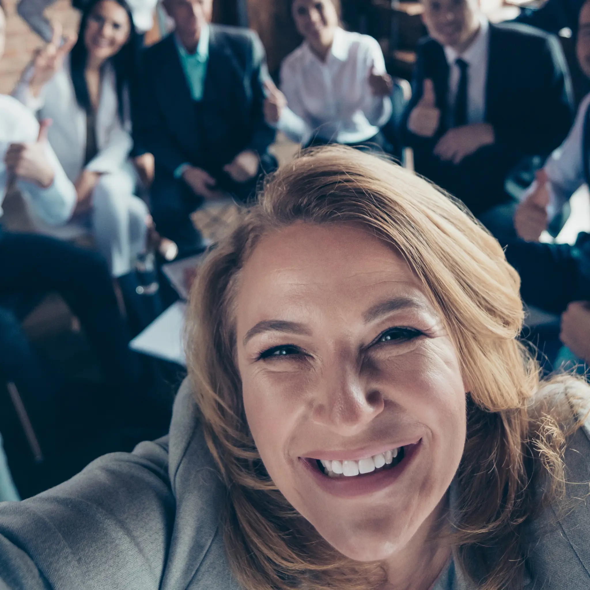 Leder som tar selfie med ansatte i bakgrunn