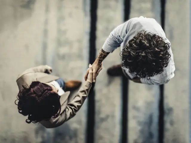 To personer tar hverandre i hånden sett ovenfra