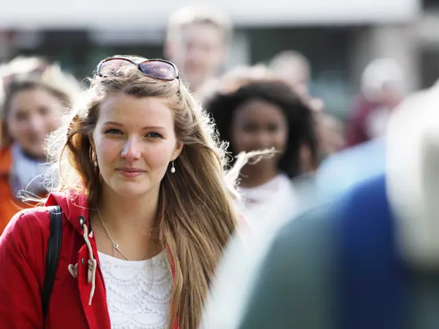 Illustrasjonsbilde av en ung kvinne stående blant mennesker som går forbi