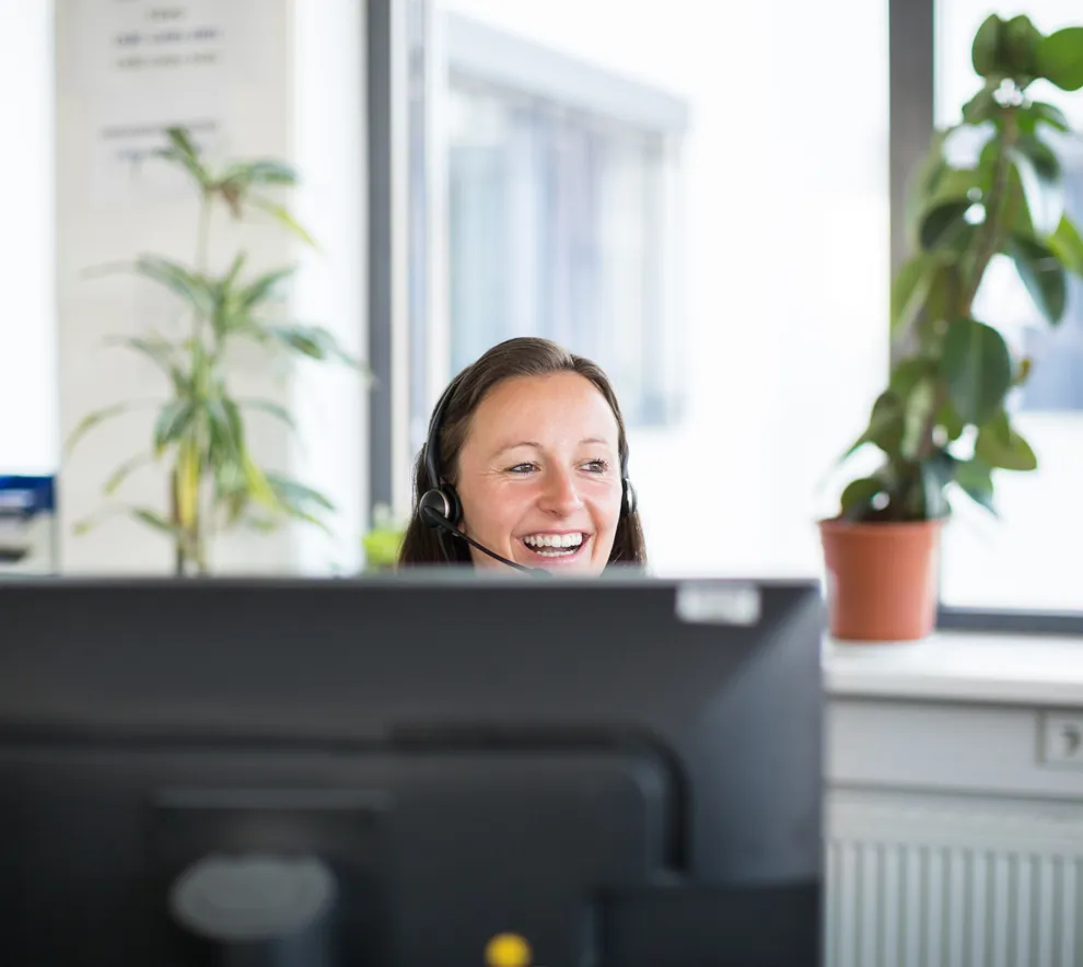 Kvinne som smiler over en PC-skjerm