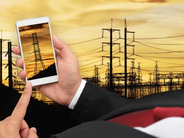 Illustrasjonsbilde av en hånd som holder en mobil med en stor strømmast både på mobilen og i bakgrunnen