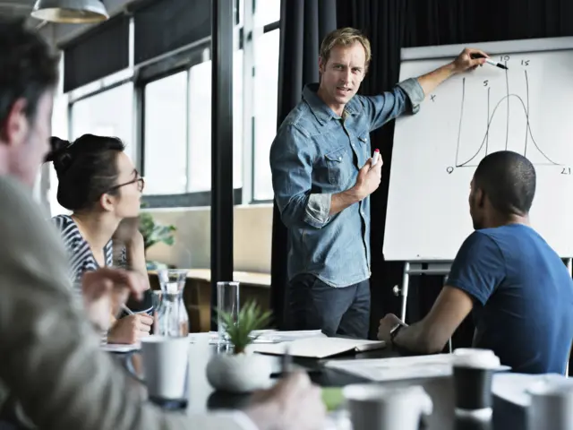 Illustrasjonsbilde av en mann som tegner på et whiteboard og holder et møte foran flere mennesker
