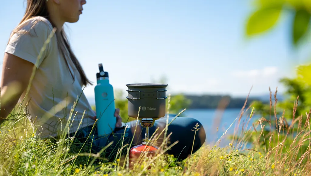 Ung kvinne ved sjøen lager mat
