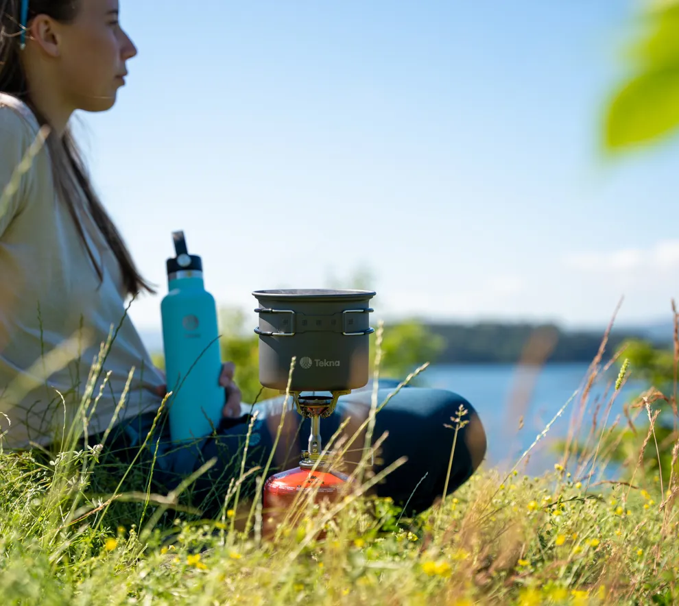 Ung kvinne ved sjøen lager mat