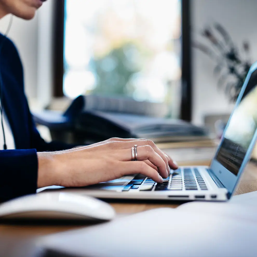 Person arbeider på bærbar PC i moderne arbeidsmiljø med fokus på digital produktivitet.