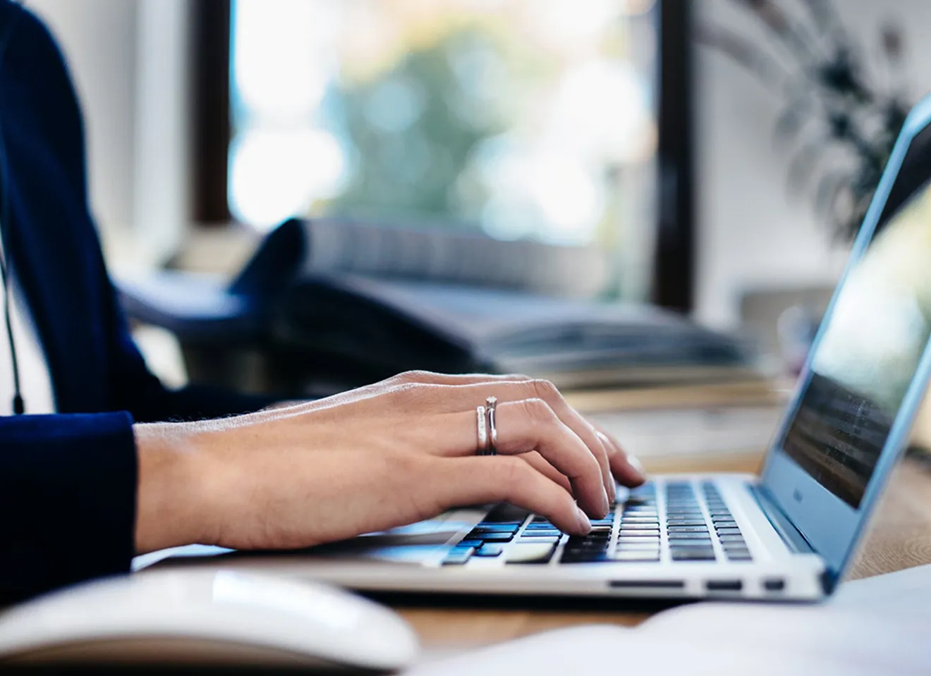 Person arbeider på bærbar PC i moderne arbeidsmiljø med fokus på digital produktivitet.