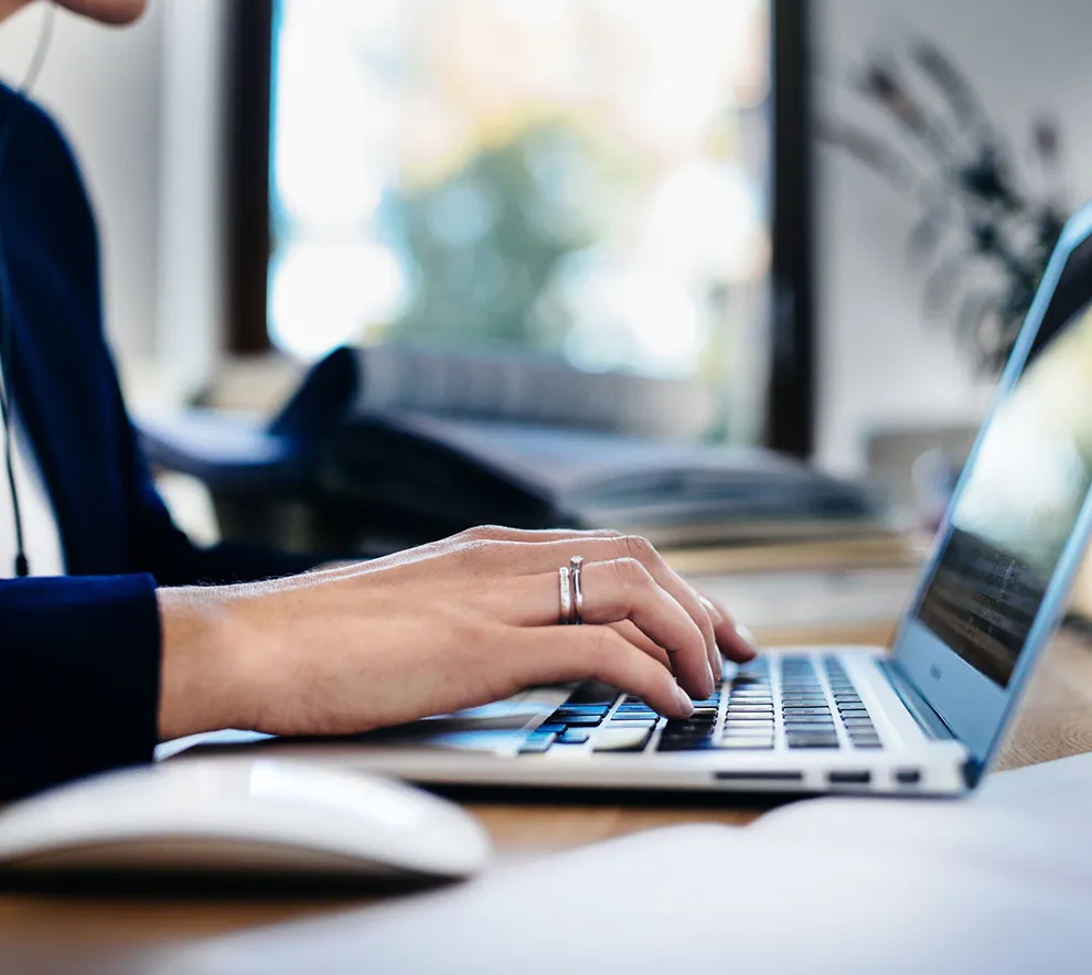 Person arbeider på bærbar PC i moderne arbeidsmiljø med fokus på digital produktivitet.