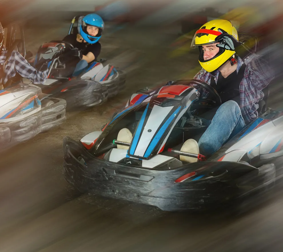 Gokartførere i full fart gjennom svingene på innendørs bane.