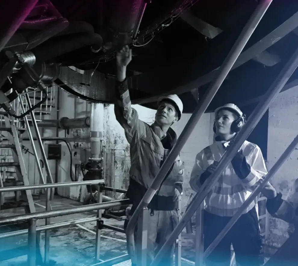 To personer med verneutstyr inspiserer teknisk utstyr i et vannkraftanlegg.