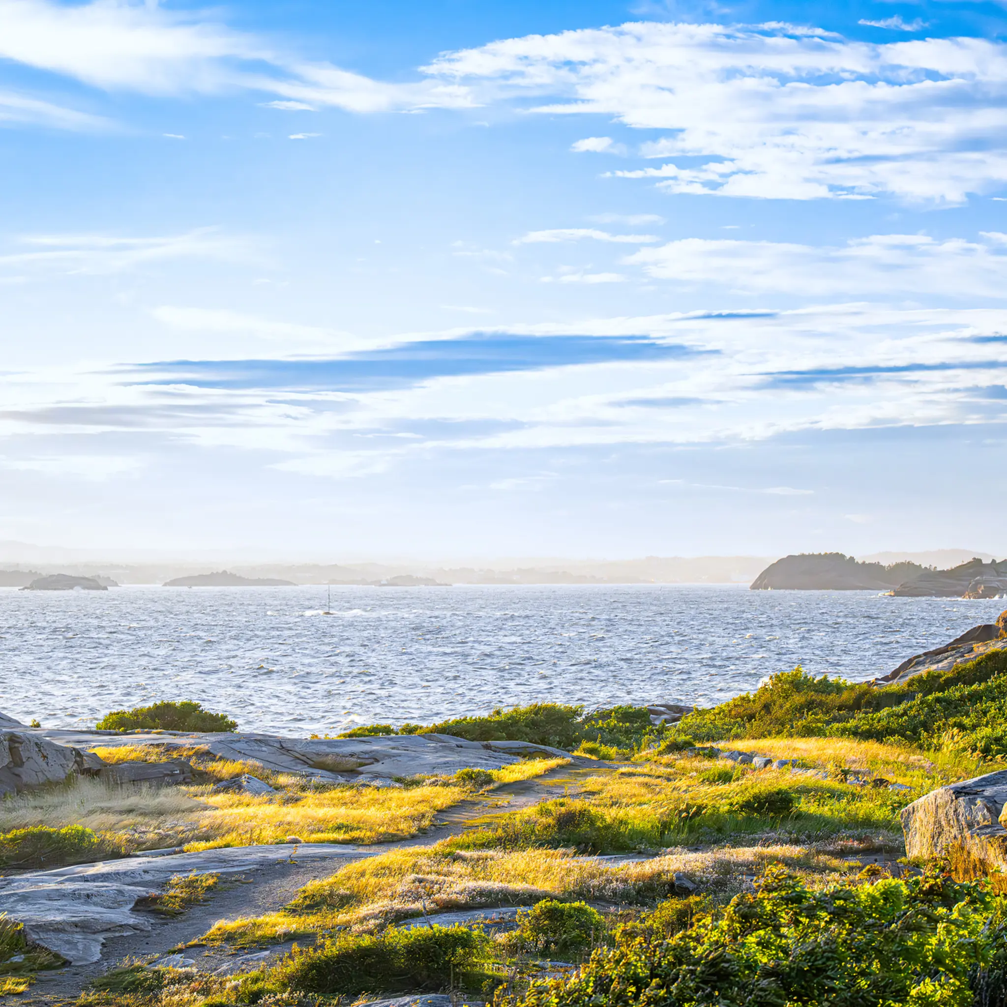 Kystlandskap med svaberg og hav i sollys langs norsk kyst