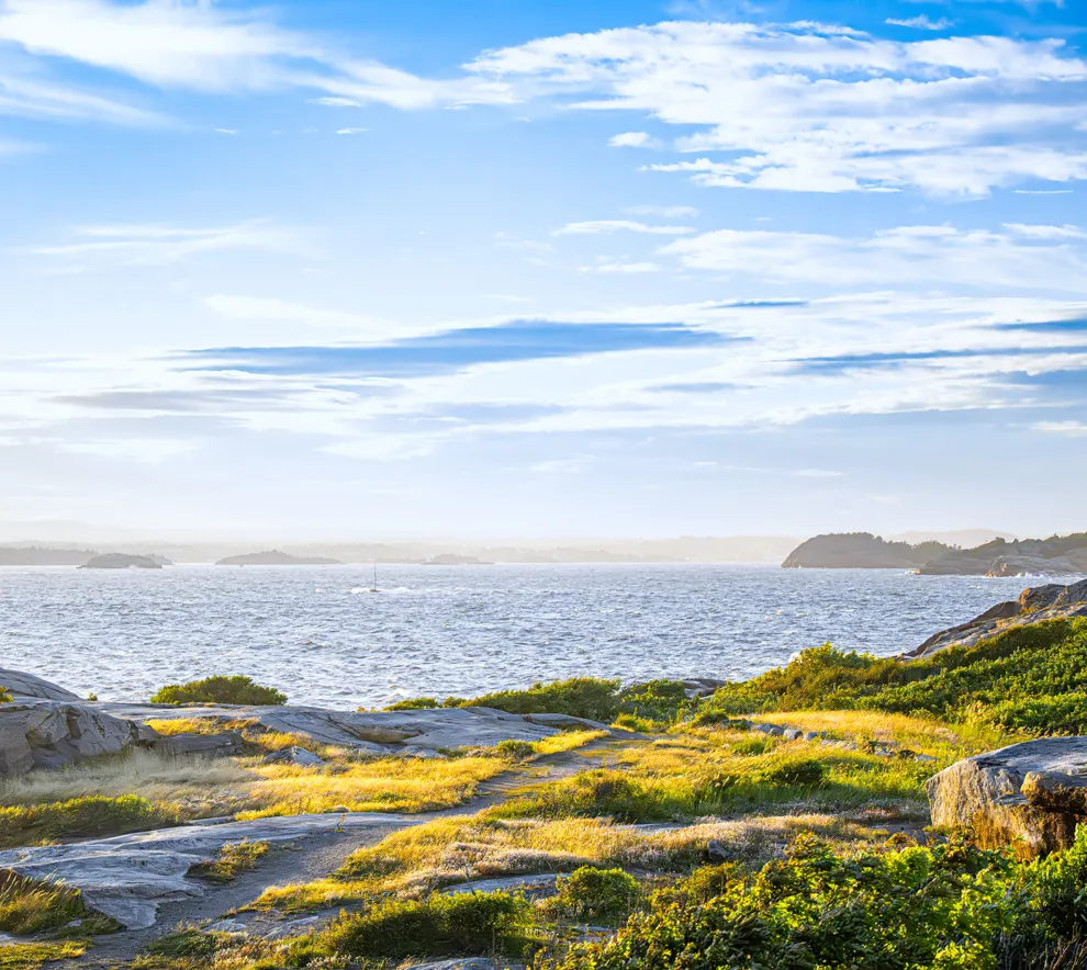 Kystlandskap med svaberg og hav i sollys langs norsk kyst