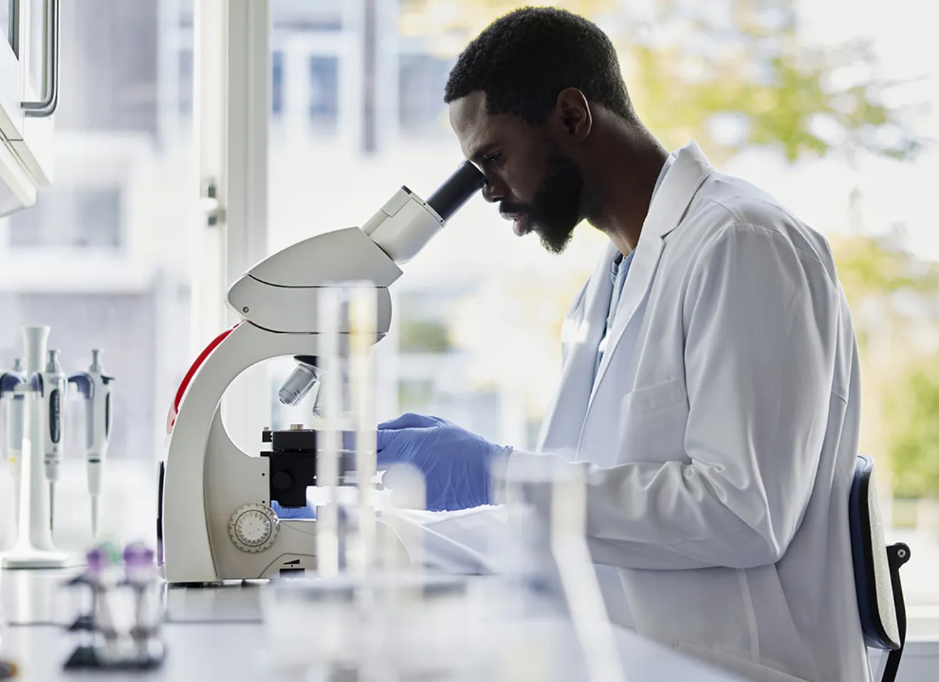 Forsker undersøker biologiske prøver i mikroskop på laboratorium.