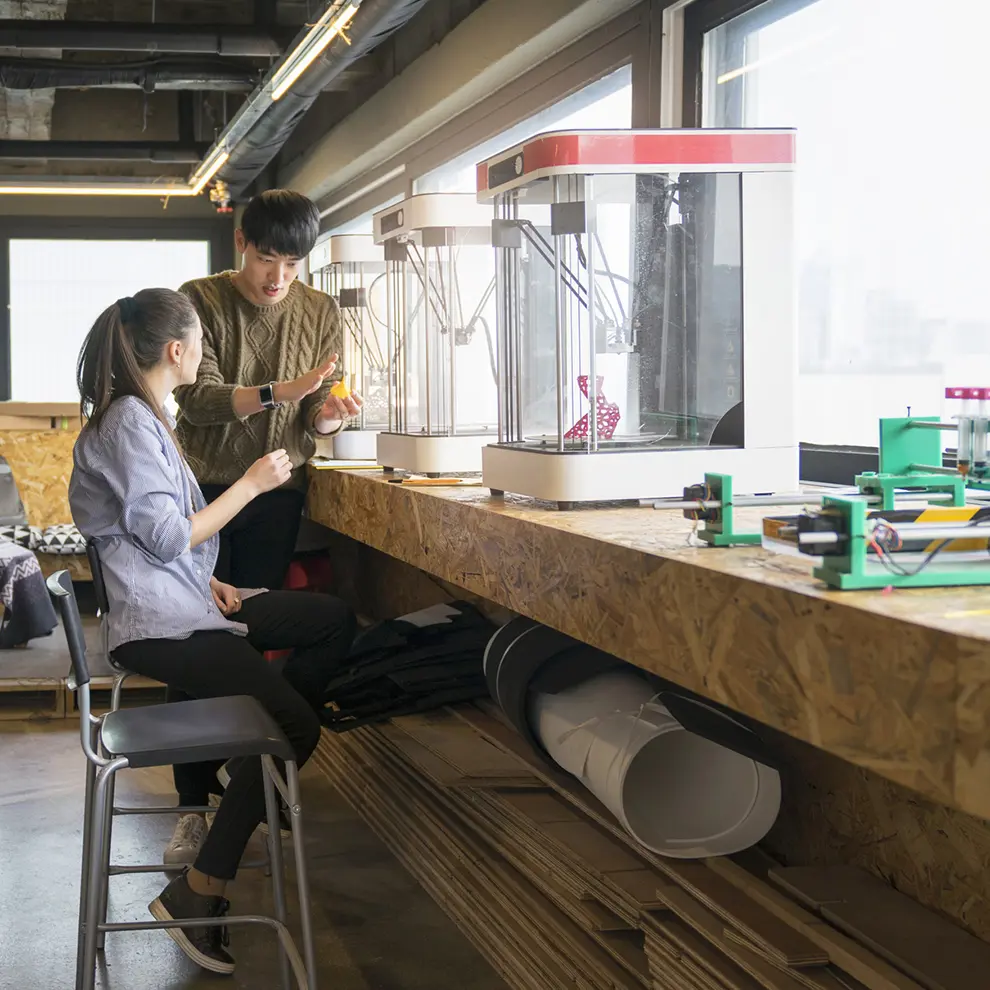 To personer utforsker 3D-printing og teknologi i et moderne makerspace.