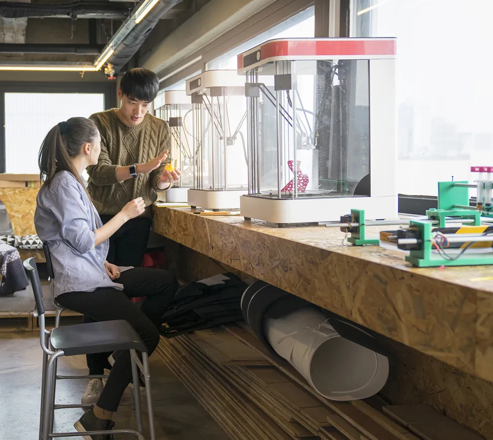 To personer utforsker 3D-printing og teknologi i et moderne makerspace.