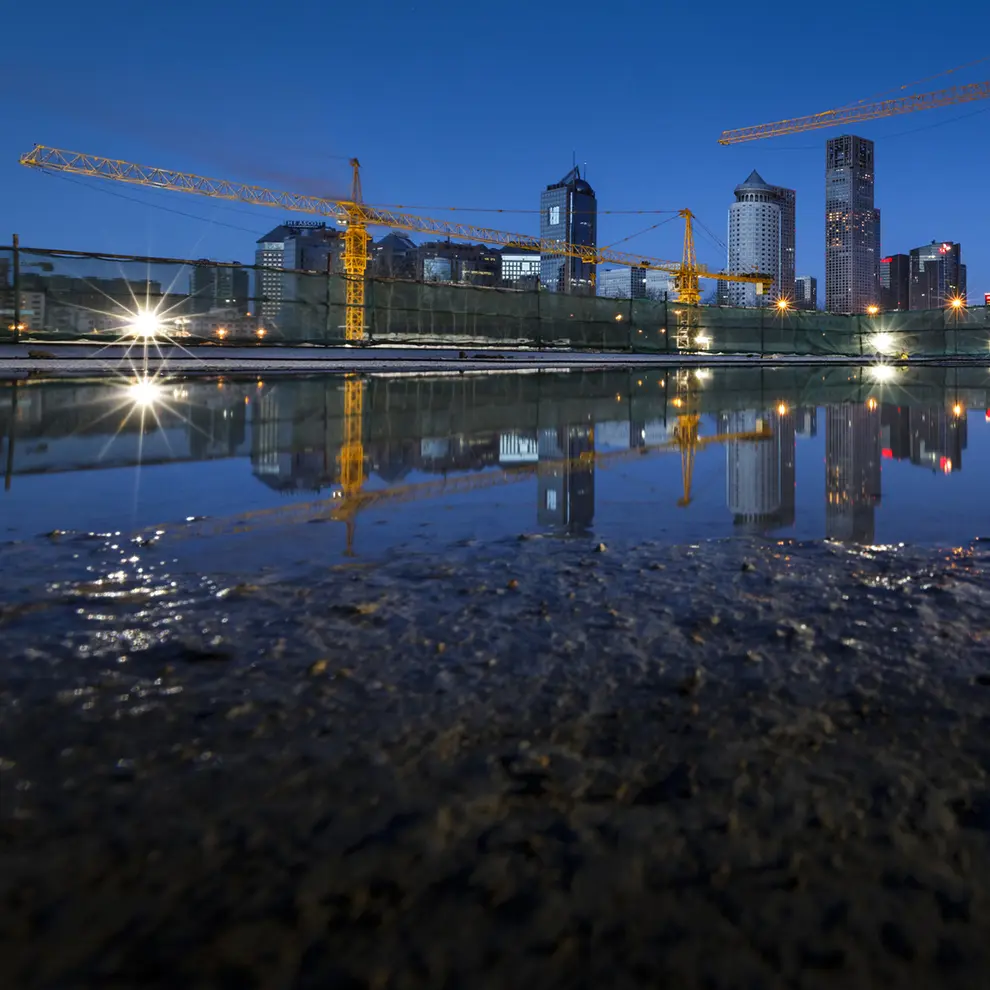 Byggeplass i by med kraner og vannspeil som viser utfordringer med overvann.