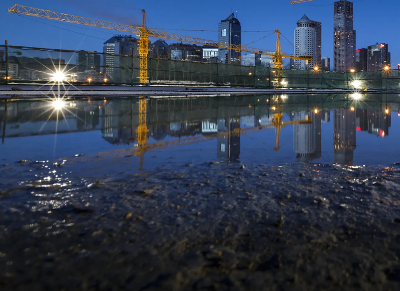 Byggeplass i by med kraner og vannspeil som viser utfordringer med overvann.