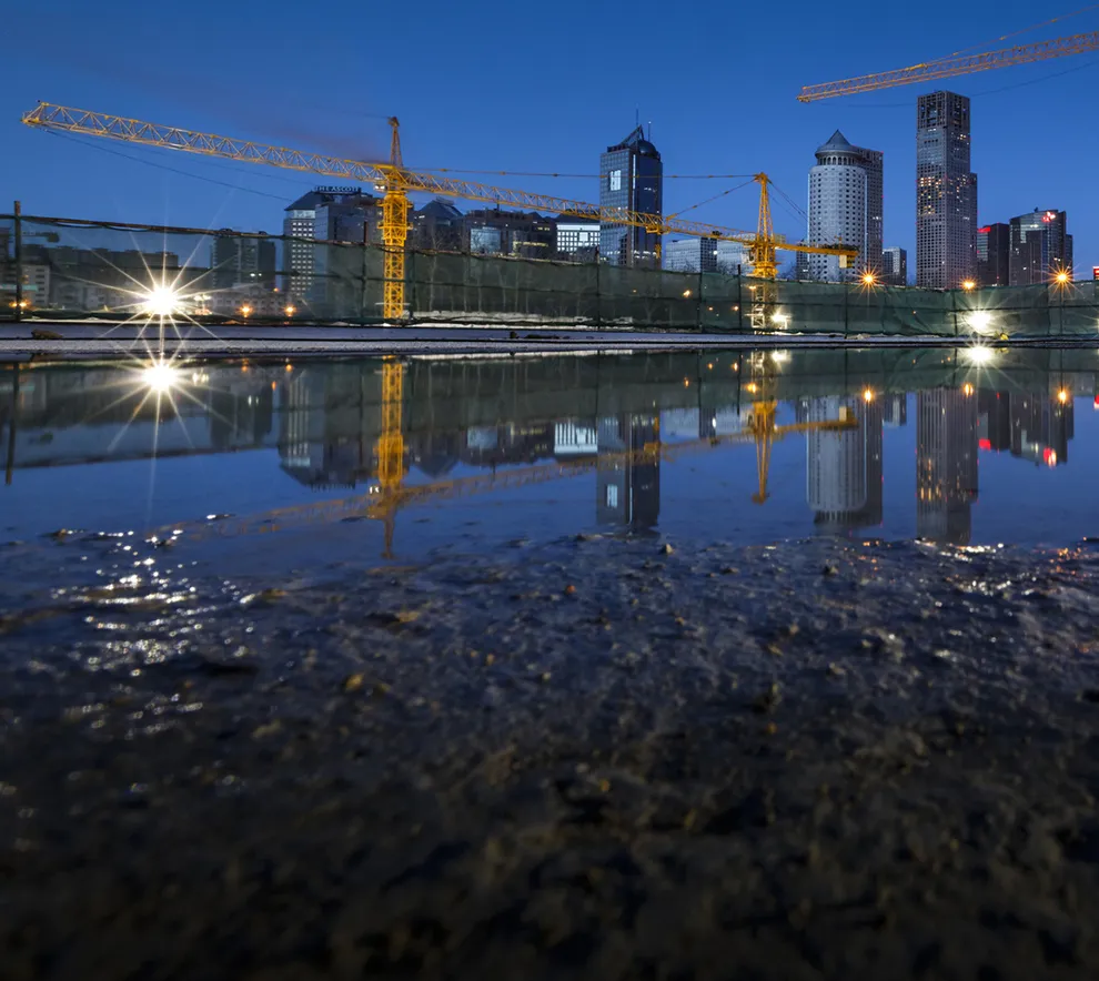 Byggeplass i by med kraner og vannspeil som viser utfordringer med overvann.