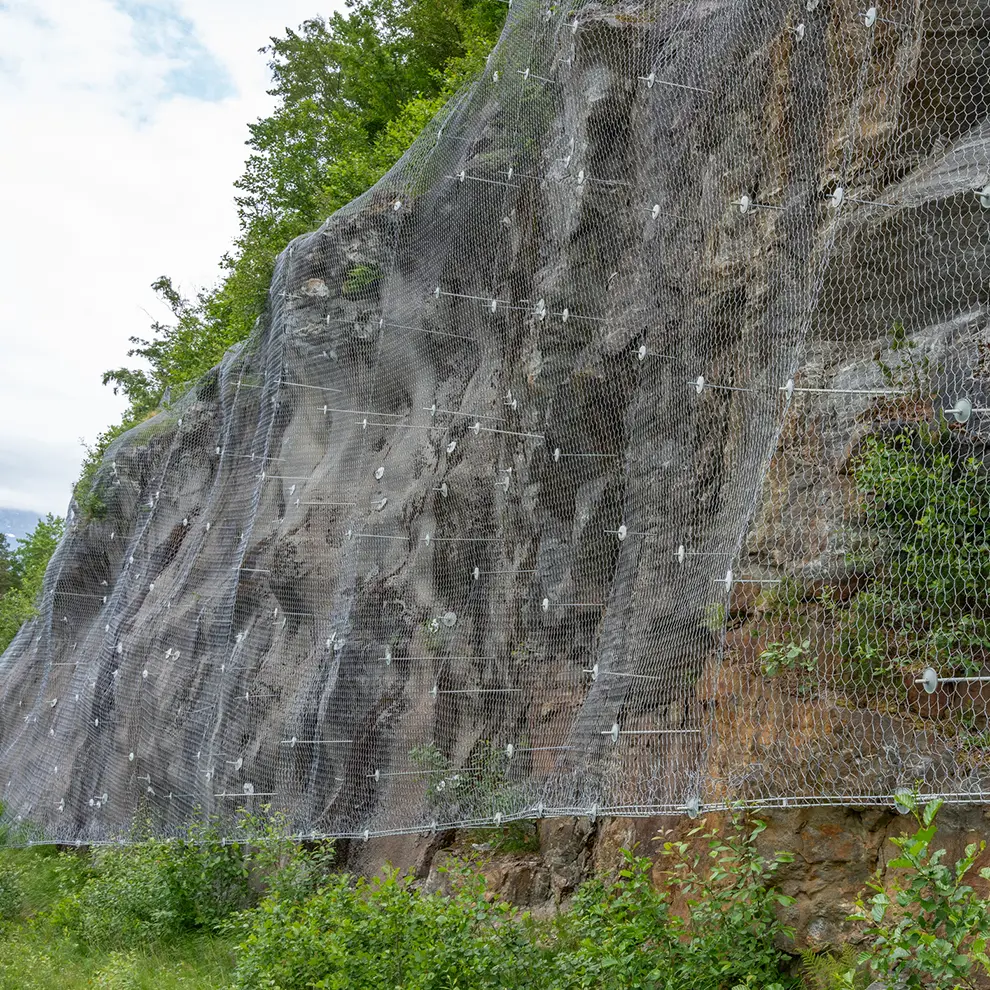 Rassikring med sikringsnett og fjellbolter på bratt fjellskråning for å hindre steinsprang og ras mot infrastruktur.