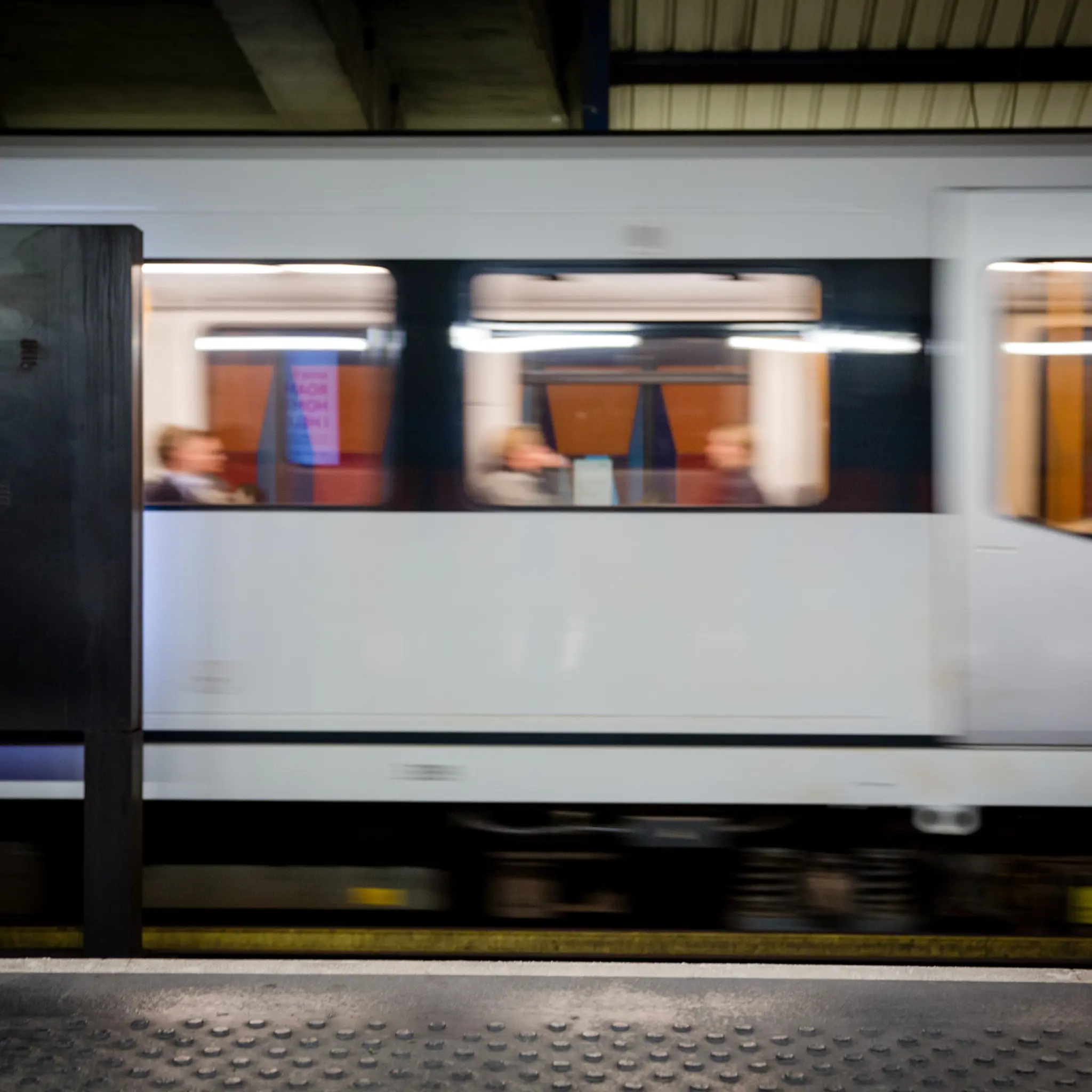 T-bane i bevegelse ved stasjon i Oslo med passasjerer om bord, illustrerer kollektivtransport og urban mobilitet.