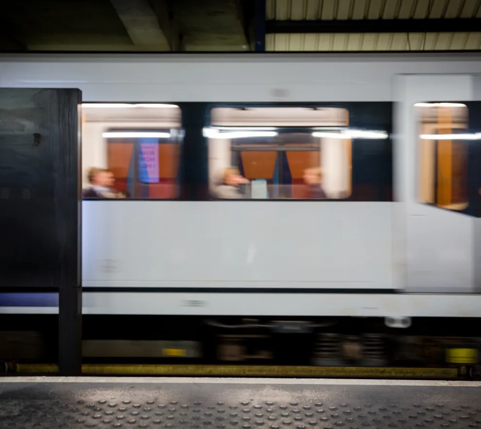 T-bane i bevegelse ved stasjon i Oslo med passasjerer om bord, illustrerer kollektivtransport og urban mobilitet.