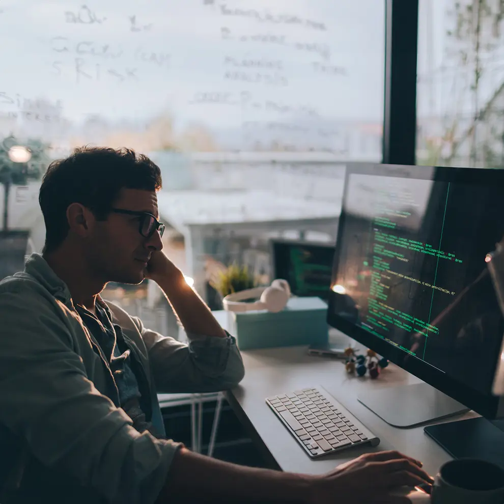 Utvikler jobber med kode på hjemmekontor foran dataskjerm med programmering i fokus.