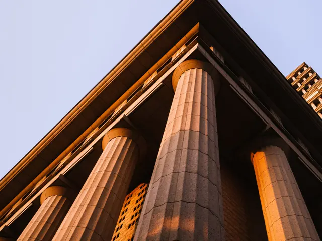 Klassisk bygning med søyler opplyst av kveldssol, symbol på jus og rettssystem.