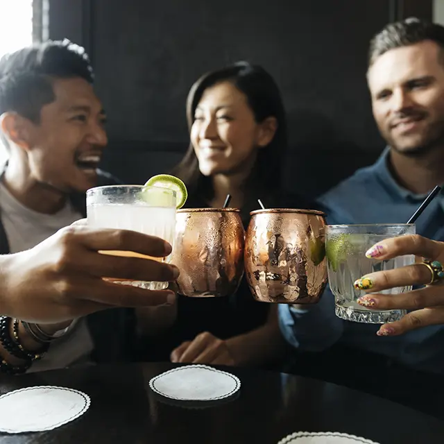 En gruppe venner koser seg på en bar, skåler.