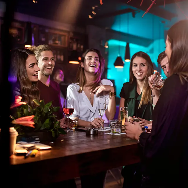 Venner står samlet rundt et bord på en bar og ler.