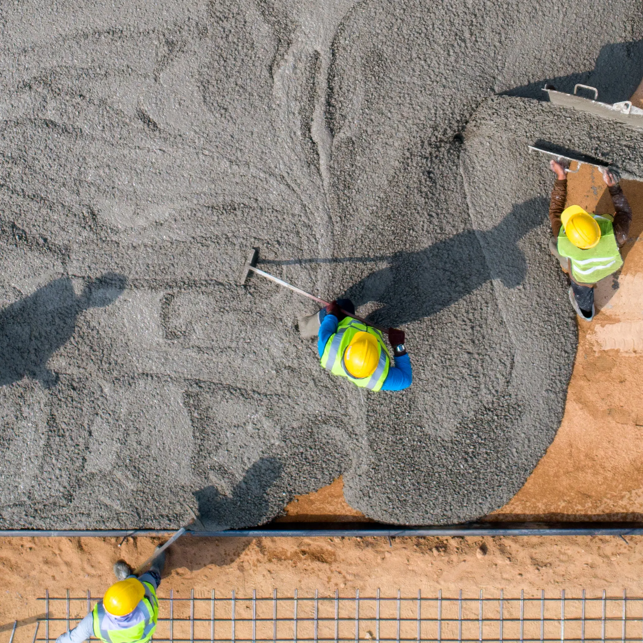 Luftbilde av en byggeplass ovenifra hvor arbeidere med en betongmaskin legger betong