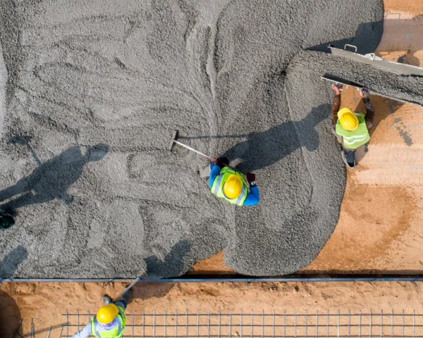 Luftbilde av en byggeplass ovenifra hvor arbeidere med en betongmaskin legger betong