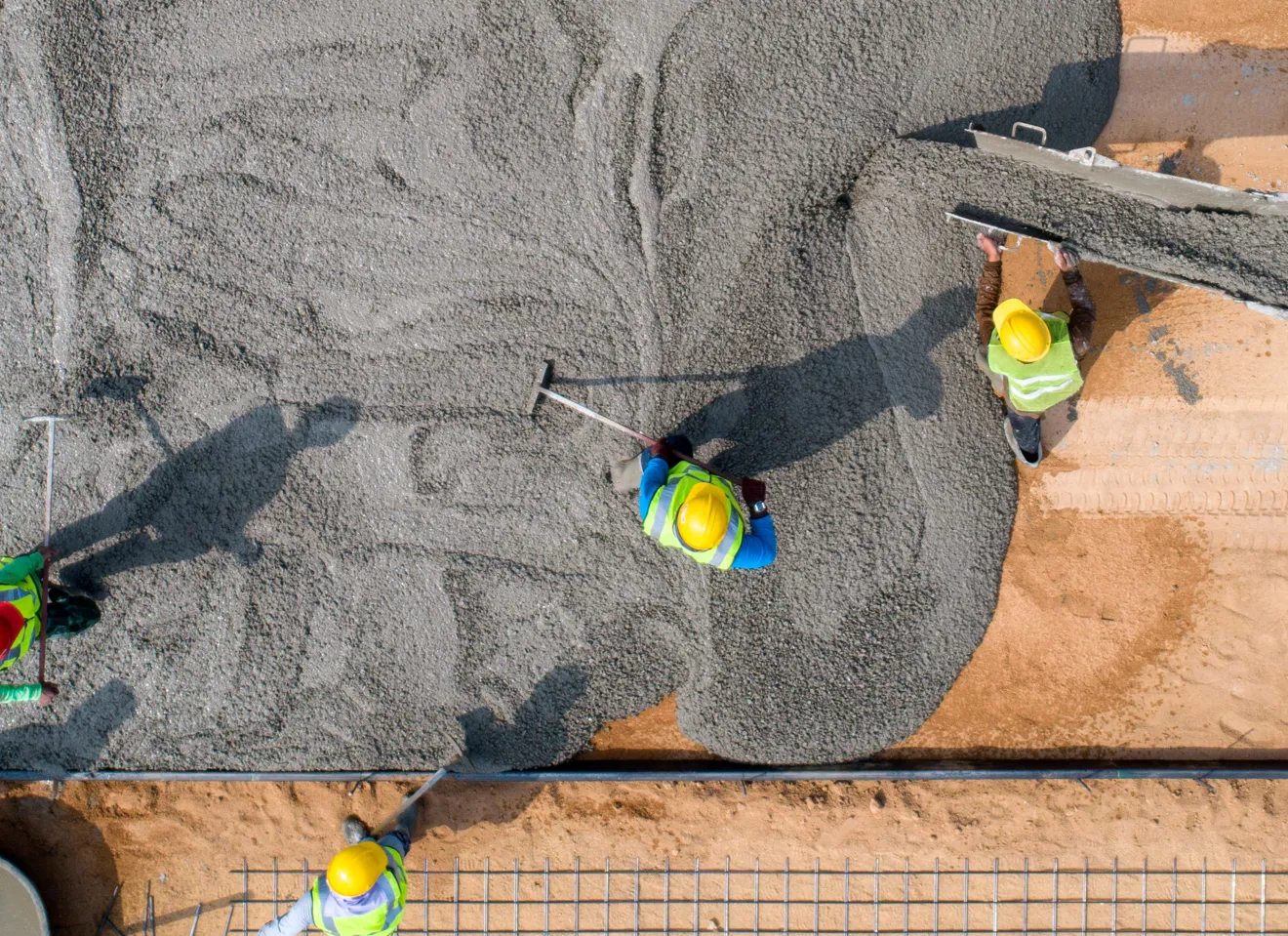 Luftbilde av en byggeplass ovenifra hvor arbeidere med en betongmaskin legger betong