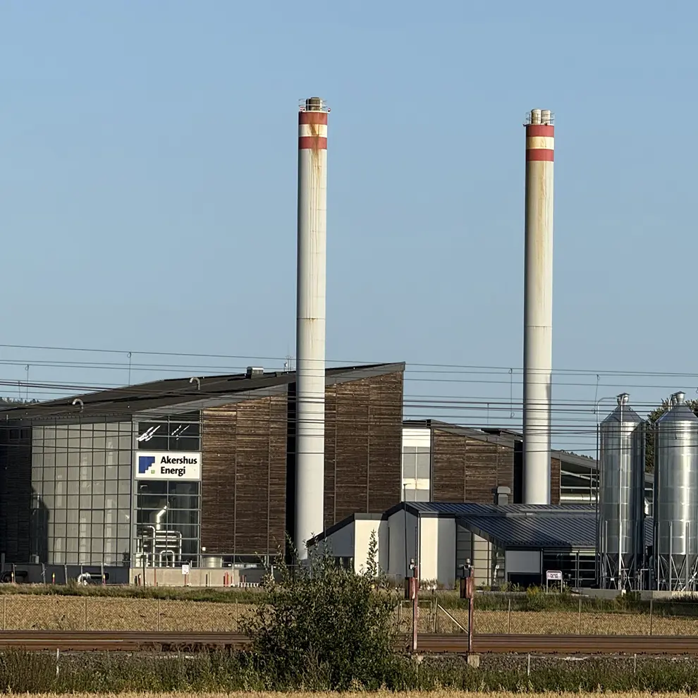 Biovarmeanlegg og fjernvarmeanlegg drevet av biomasse, med industribygg og piper ved Akershus Energi.