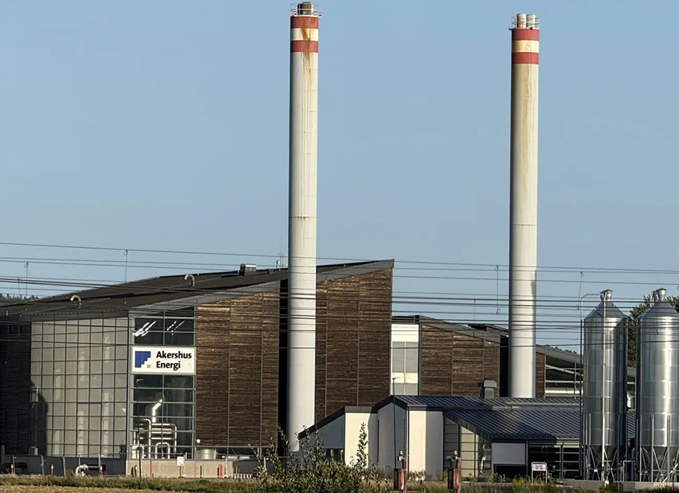 Biovarmeanlegg og fjernvarmeanlegg drevet av biomasse, med industribygg og piper ved Akershus Energi.