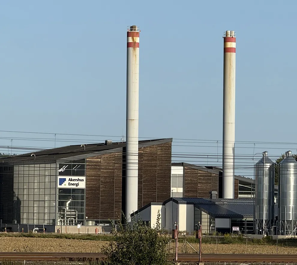 Biovarmeanlegg og fjernvarmeanlegg drevet av biomasse, med industribygg og piper ved Akershus Energi.