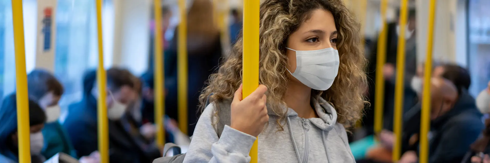 Ung kvinne på offentligtransport med munnbind 