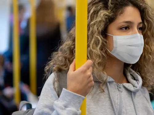 Ung kvinne på offentligtransport med munnbind 