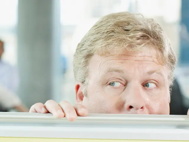 mann gjemmer seg nesten under bordet