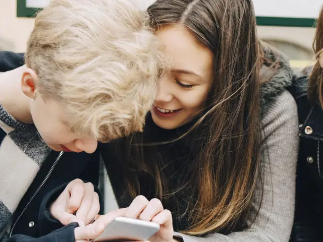 Tre barn samarbeider om noe på mobil