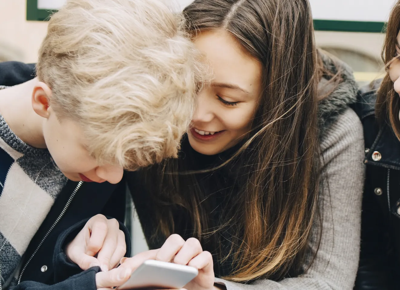 Tre barn samarbeider om noe på mobil