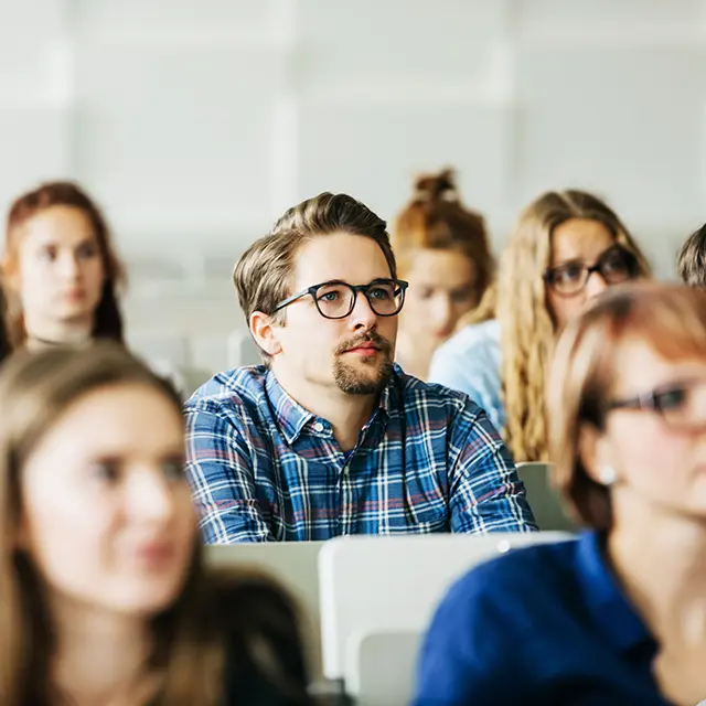 Nærbile av studenter i forelesningssal mann med briller i fokus