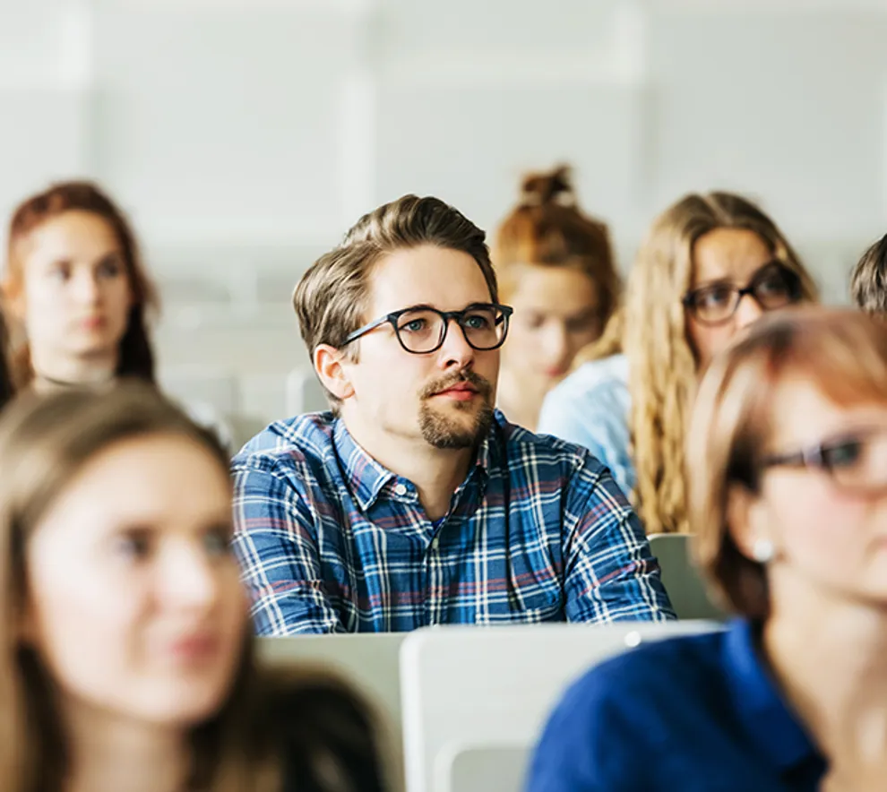 Nærbile av studenter i forelesningssal mann med briller i fokus