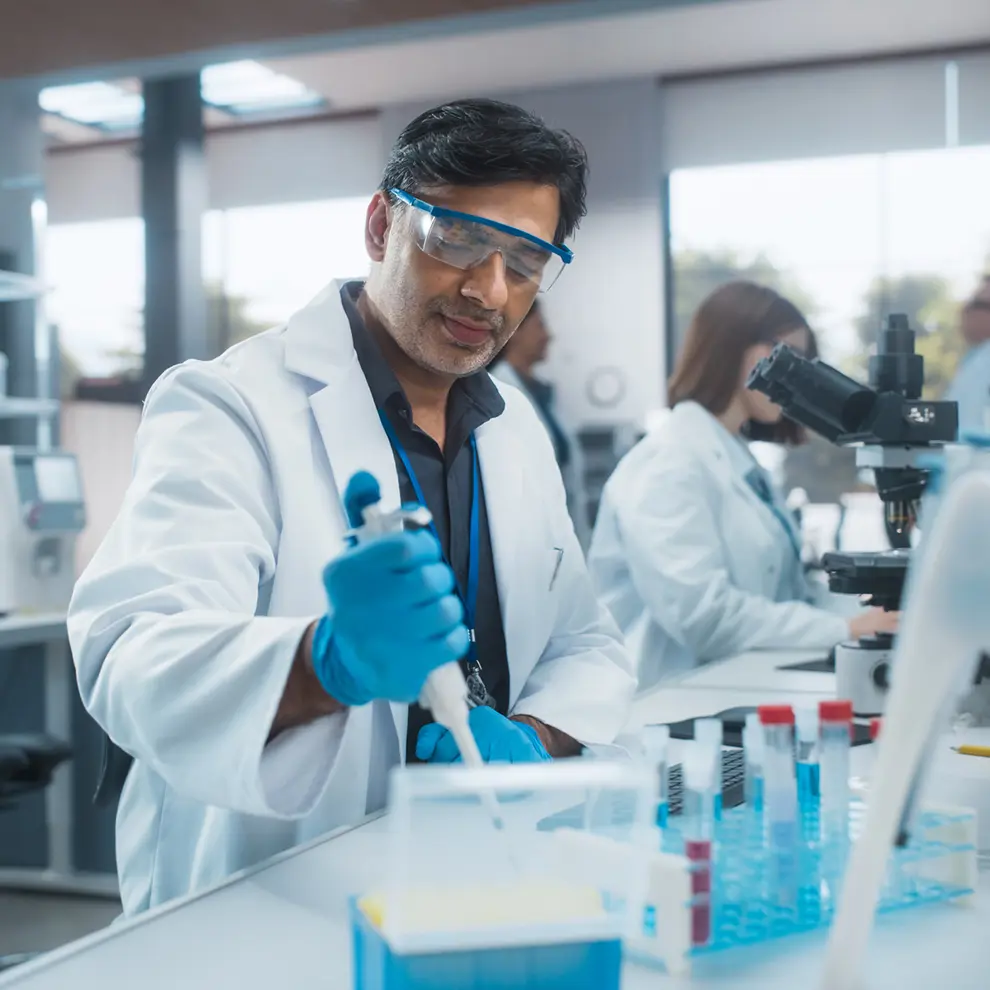 Forsker i laboratoriet som jobber med pipette og genteknologiske analyser.