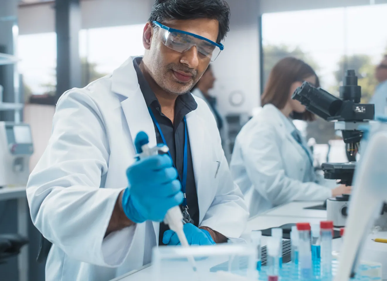 Forsker i laboratoriet som jobber med pipette og genteknologiske analyser.