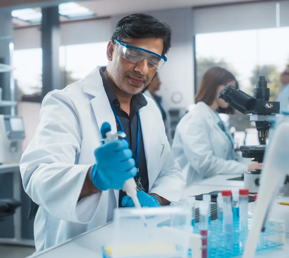 Forsker i laboratoriet som jobber med pipette og genteknologiske analyser.